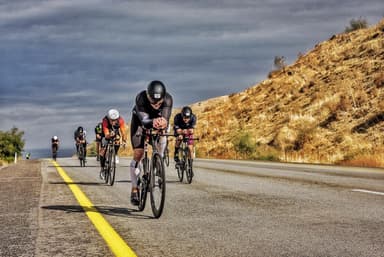 Triathletes on time trial bikes on the bike course, on a dry hillside road.