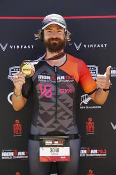 Christian Plesca holding up the finisher medal at the IRONMAN 70.3 World Championship.