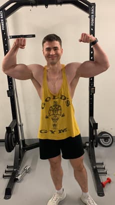 Christian Plesca in a Gold’s Gym tank top in front of a power rack in the gym.