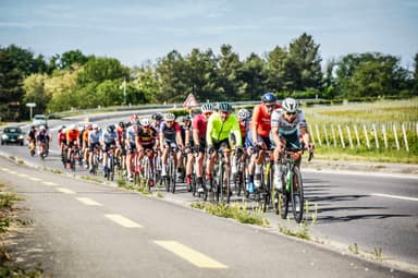 A large group of cyclists riding together in the bunch during a road cycling event.